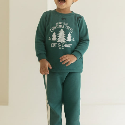 Child wearing a teal outfit with a graphic design, standing in front of a white curtain with small lights.