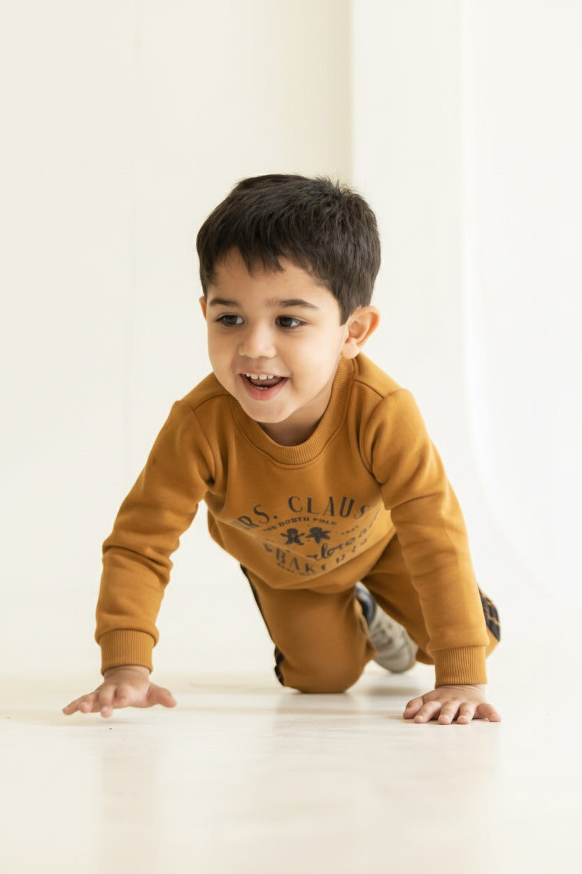 Child in a mustard yellow sweater crawling on a light-colored floor with a neutral background