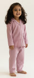 Young girl wearing pink striped pajamas standing against a beige background