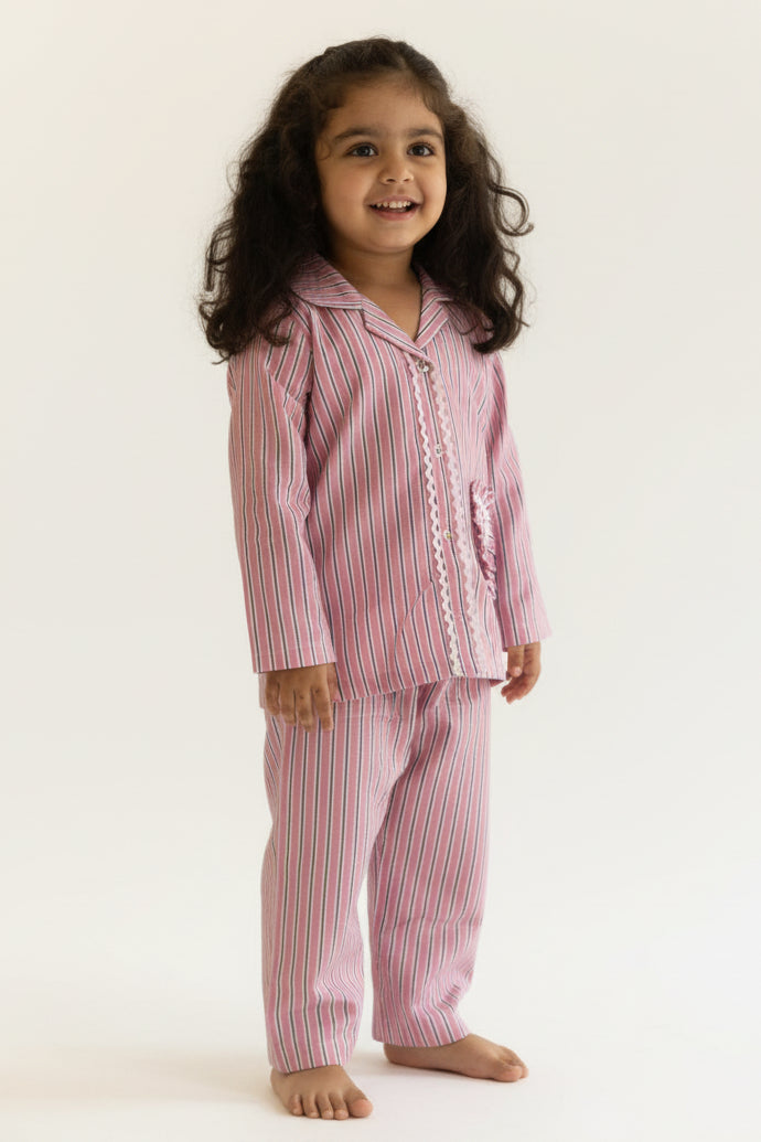Young girl wearing pink striped pajamas standing against a beige background