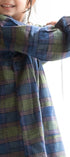 Child wearing a plaid dress standing by a window