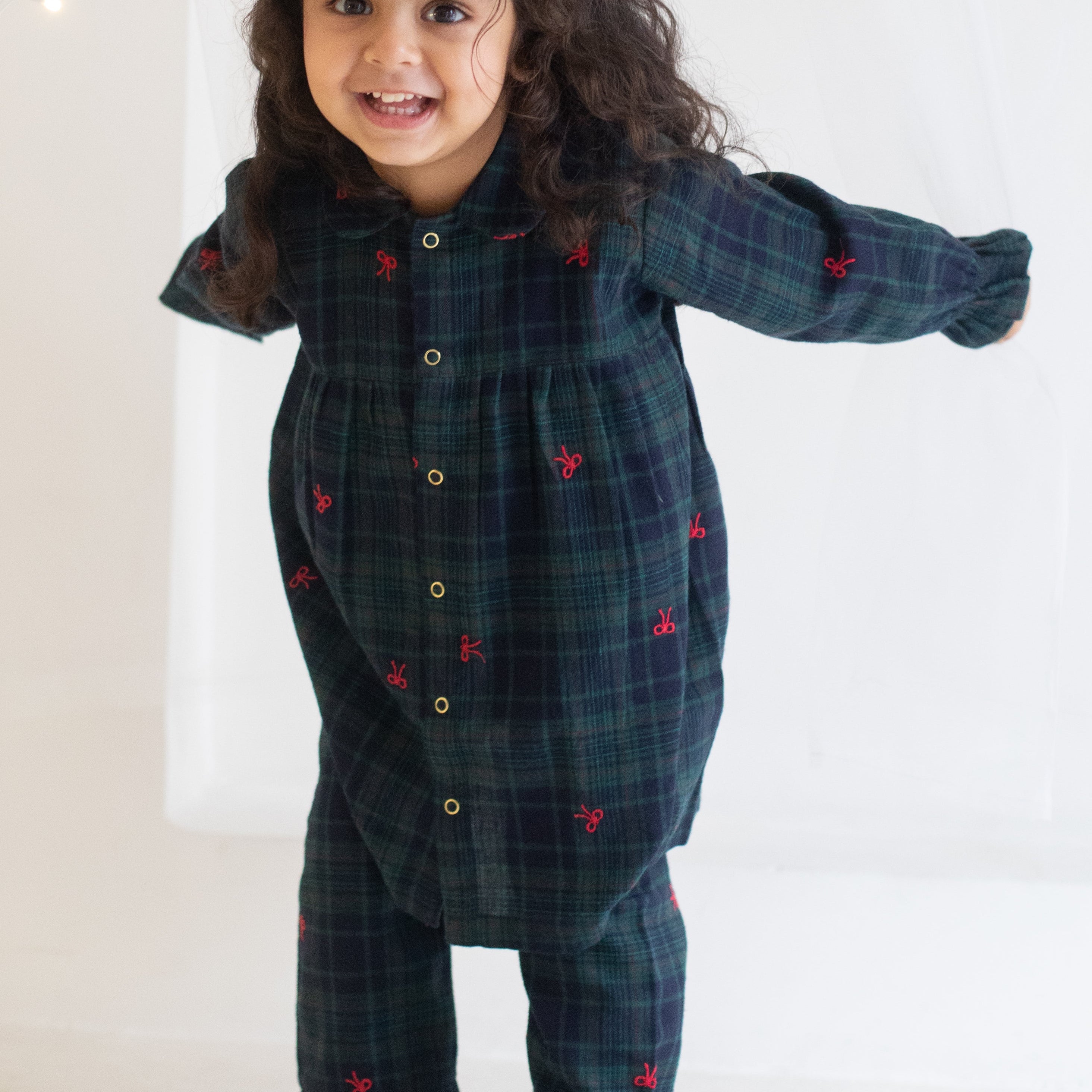 Child wearing a dark blue plaid outfit with red heart patterns on a white background