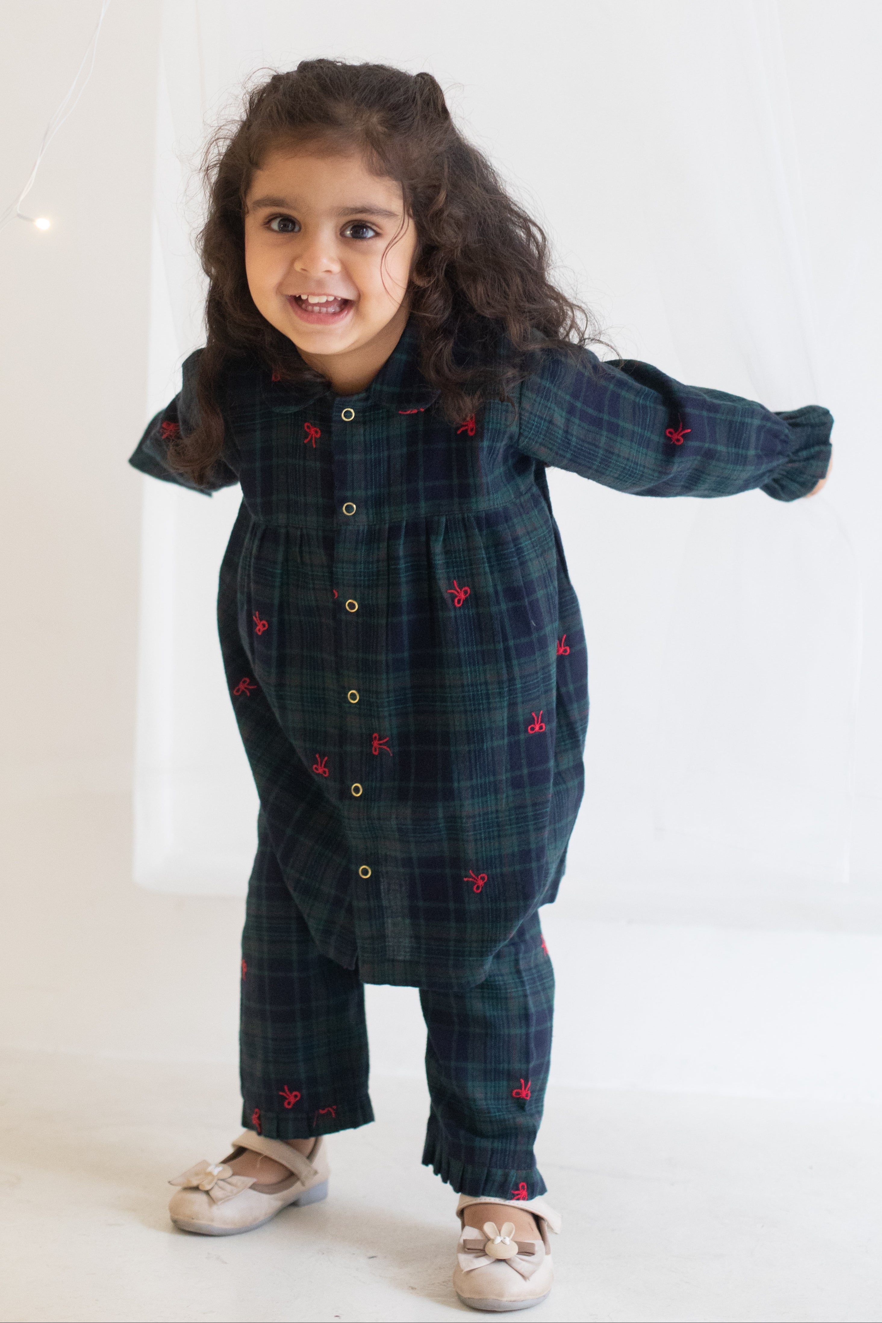 Child wearing a dark blue plaid outfit with red heart patterns on a white background