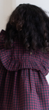 Person wearing a red and black checkered dress with long, dark hair.