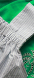 Close-up of a green fabric with intricate silver embroidery and a white striped fabric.