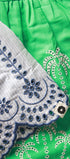Close-up of green fabric with white embroidery and a white border with blue embroidery.