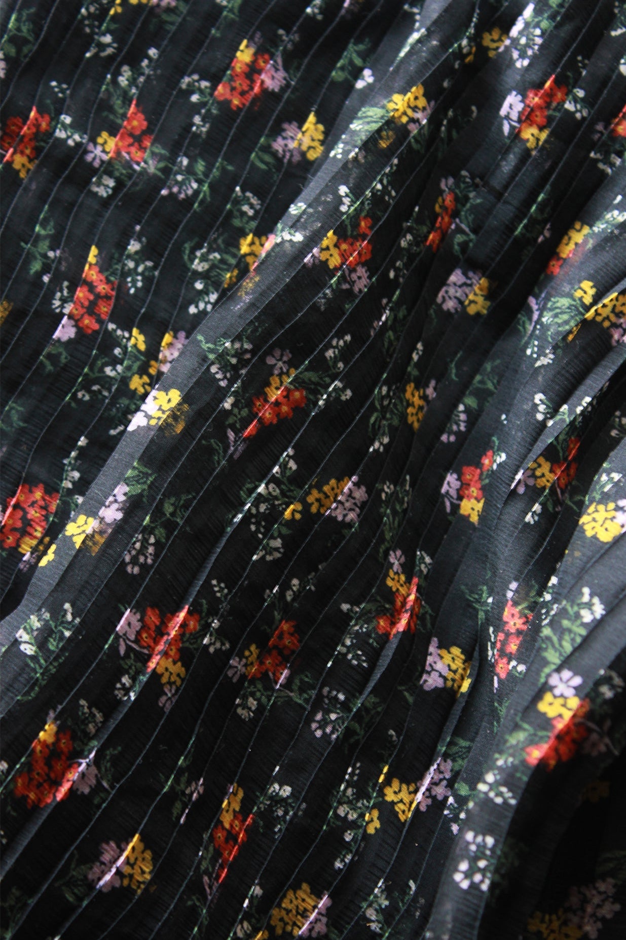 Close-up of pleated fabric with floral pattern on a black background