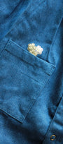 Close-up of a blue jacket with a floral PATCH on the chest pocket.
