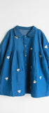 Blue dress with white floral embroidery on a light gray background