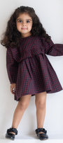 Young girl wearing a red and black checkered dress against a white background