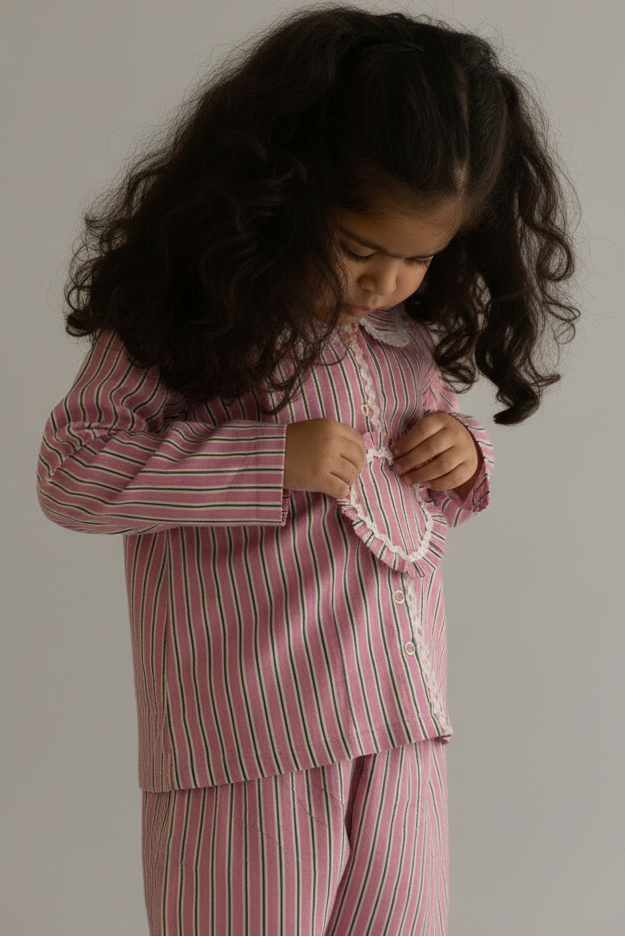 Child wearing a pink and red striped outfit against a beige wall.