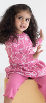 Young girl wearing a pink outfit with white patterns on a white background