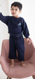 Child wearing a navy blue outfit with 'Chase' text, standing on a pink chair against a white background