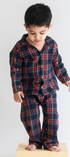 Child wearing a navy and red plaid pajama set on a white background