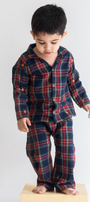 Child wearing a navy and red plaid pajama set on a white background