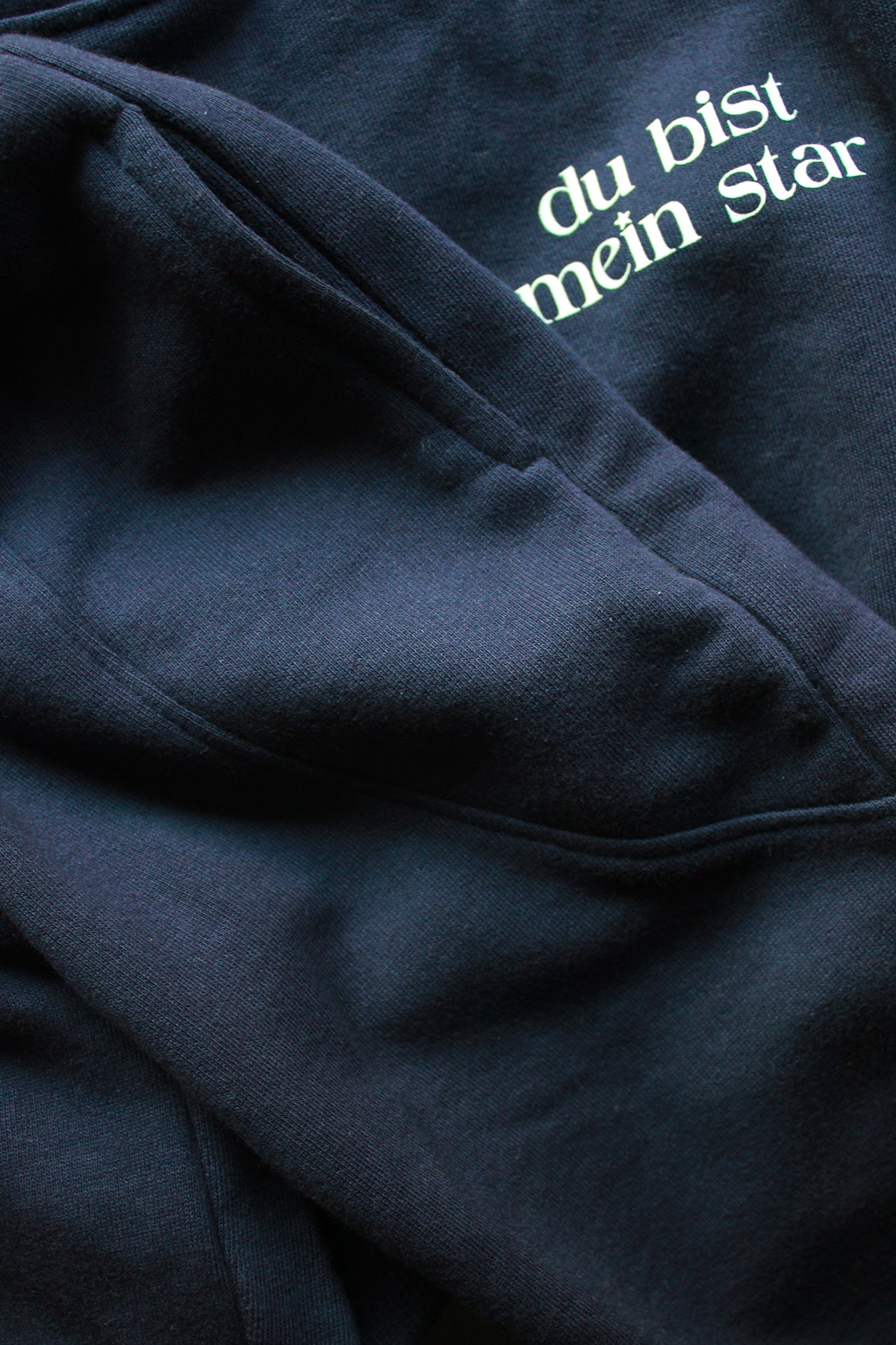Navy blue sweatshirt with white text 'du bist mein Star' on a dark background