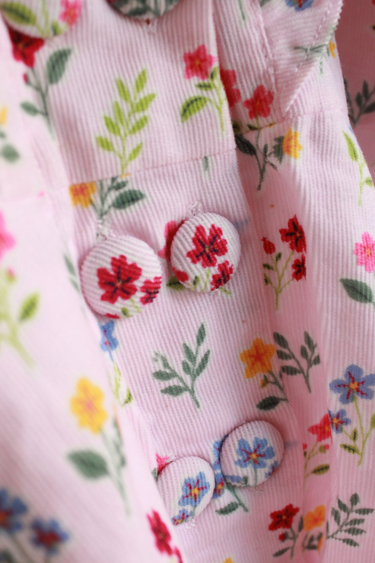 Close-up of a pink fabric with floral patterns and buttons.